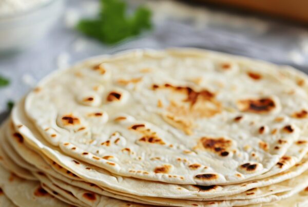 A stack of flour tortillas, resting on a grey linen napkin